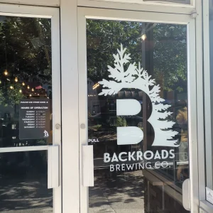 white cut vinyl logo and lettering window graphics applied to the glass door of the entrance to a brewery